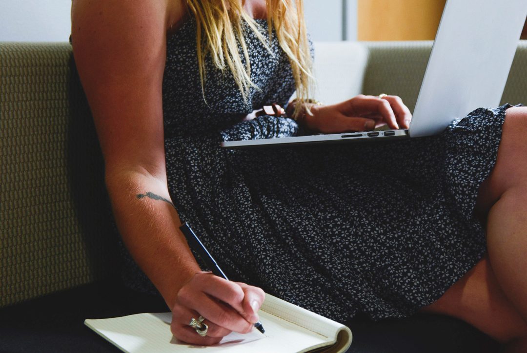 mano de mujer tomando notas junto a ordenador